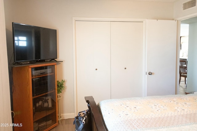 bedroom with visible vents, a closet, and wood finished floors