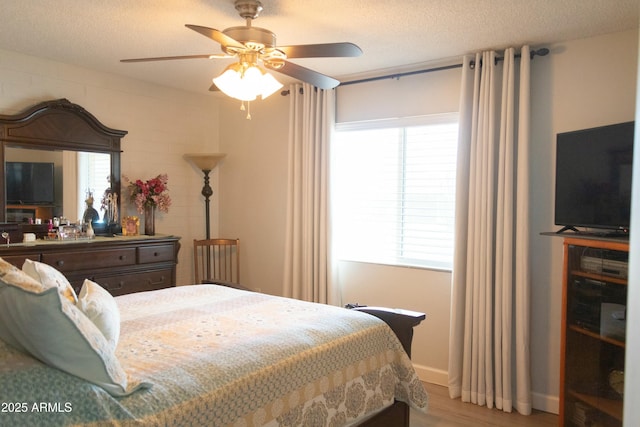 bedroom with ceiling fan, a textured ceiling, and light wood-style floors