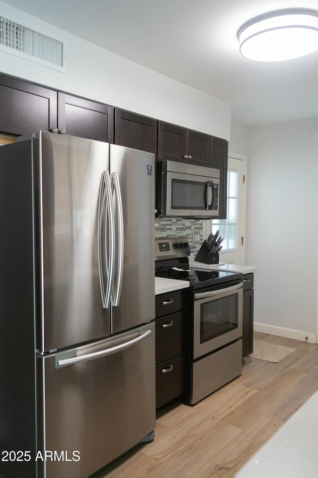 kitchen featuring visible vents, light wood-style flooring, light countertops, appliances with stainless steel finishes, and tasteful backsplash