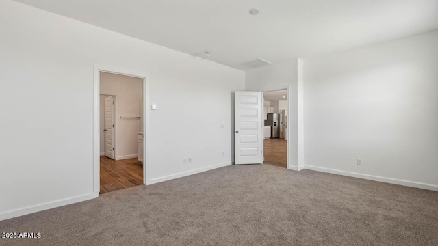 unfurnished bedroom featuring baseboards, connected bathroom, and carpet