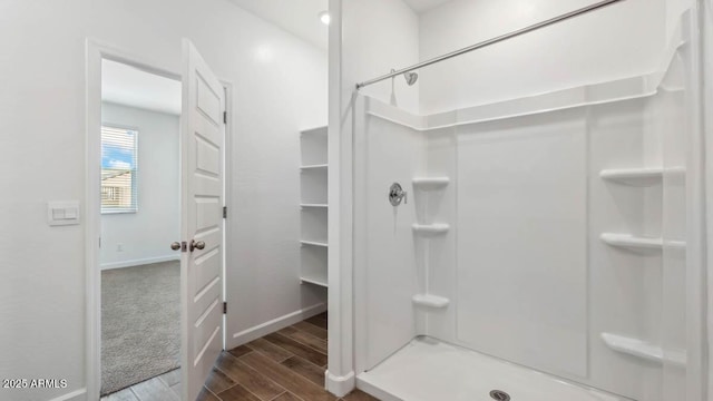 bathroom featuring a shower stall, wood finish floors, and baseboards