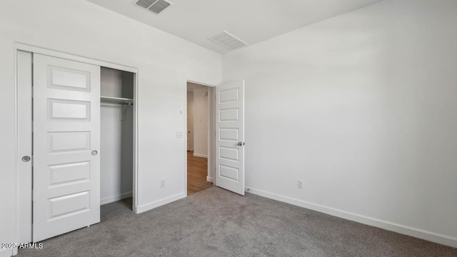 unfurnished bedroom with carpet, visible vents, baseboards, and a closet