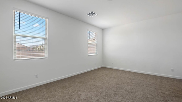 empty room with carpet flooring, visible vents, and baseboards