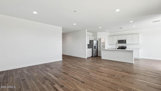 unfurnished living room featuring recessed lighting, wood finished floors, a sink, baseboards, and visible vents
