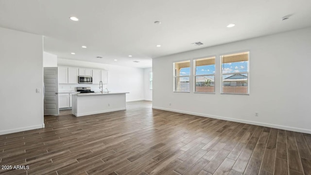 unfurnished living room with dark wood finished floors, visible vents, and a healthy amount of sunlight