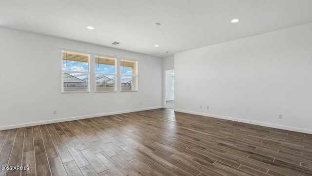 spare room with dark wood-type flooring, visible vents, recessed lighting, and baseboards