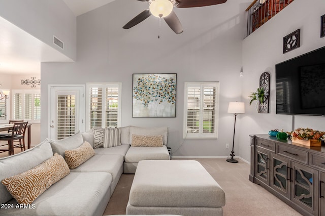 living room with light colored carpet, ceiling fan with notable chandelier, and high vaulted ceiling