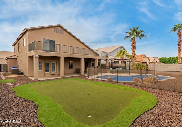 back of property featuring central AC unit, a fenced in pool, a balcony, and a patio area