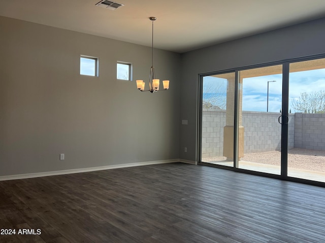 spare room featuring dark hardwood / wood-style flooring and a chandelier