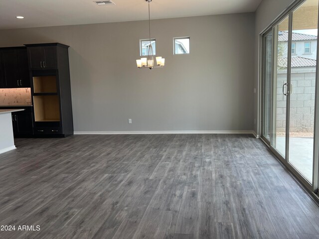 unfurnished dining area featuring a notable chandelier and dark hardwood / wood-style flooring