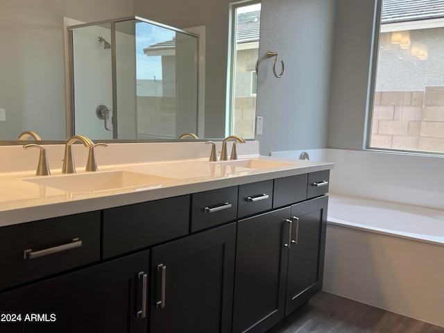 bathroom with plus walk in shower, dual bowl vanity, and wood-type flooring