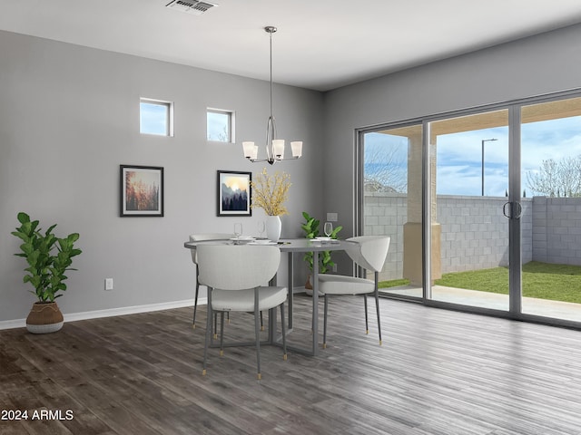 dining area with hardwood / wood-style floors and an inviting chandelier