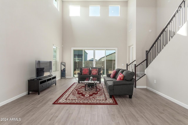 living room with light hardwood / wood-style floors, a high ceiling, and a wealth of natural light