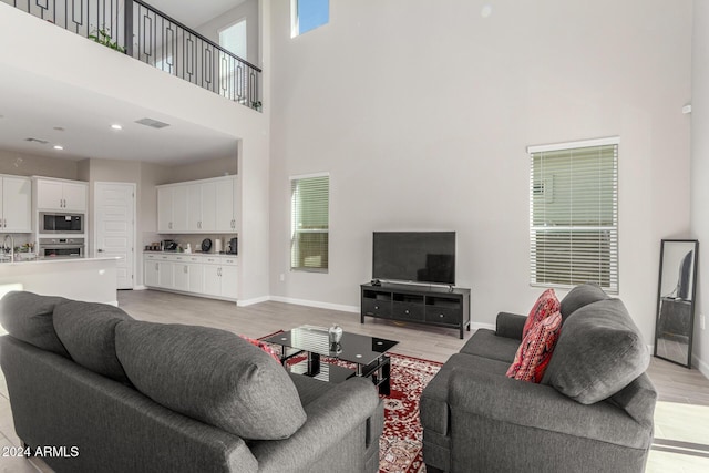 living room featuring a towering ceiling, light hardwood / wood-style flooring, and sink