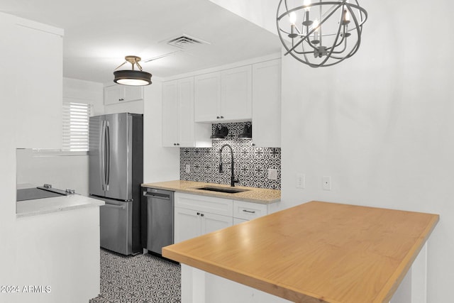 6125 E Indian School Rd Unit 240, Scottsdale, AZ 85251 - kitchen featuring a sink, appliances with stainless steel finishes, a chandelier, decorative backsplash, and white cabinetry