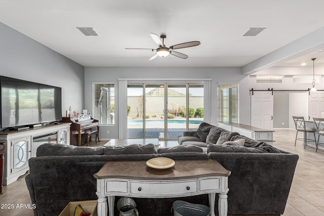 living room featuring a barn door, a ceiling fan, and healthy amount of natural light