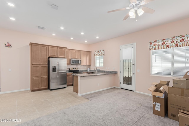 kitchen with appliances with stainless steel finishes, a peninsula, ceiling fan, light carpet, and baseboards