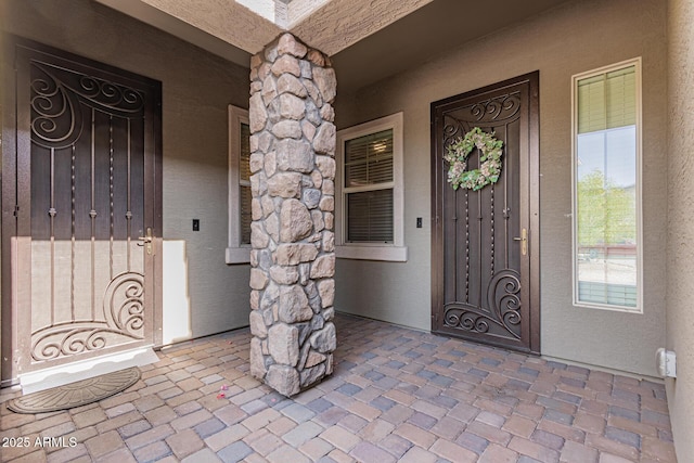 entrance to property with a porch and stucco siding