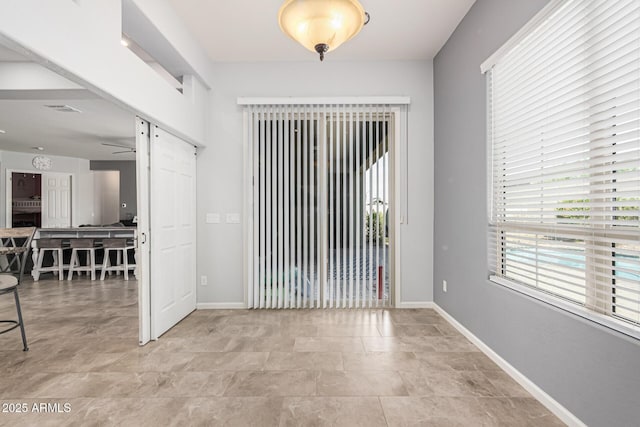 unfurnished room with baseboards and stone finish floors