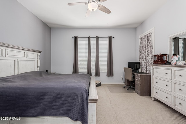 bedroom featuring light carpet, ceiling fan, a desk, and baseboards
