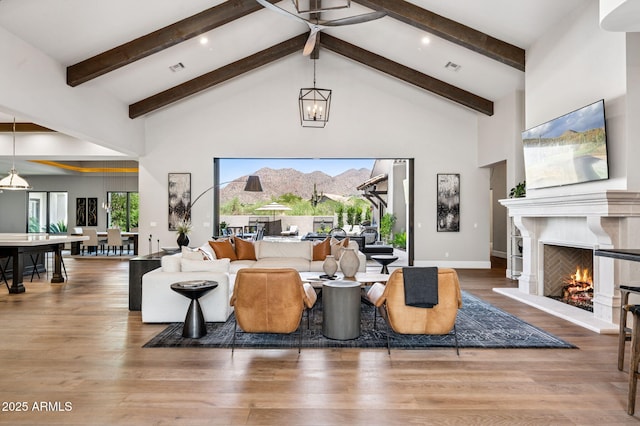 13750 E Yucca St, Scottsdale, AZ 85259 - living area featuring high vaulted ceiling, a warm lit fireplace, beam ceiling, wood finished floors, and baseboards