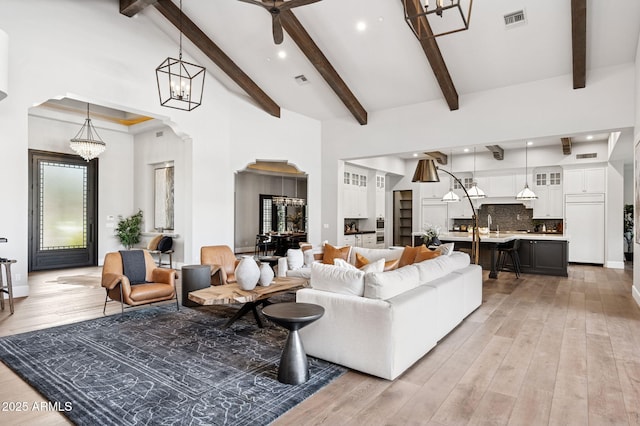 13750 E Yucca St, Scottsdale, AZ 85259 - living area featuring arched walkways, light wood-style floors, beam ceiling, a chandelier, and recessed lighting