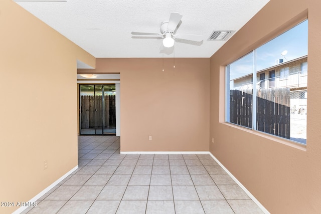 tiled empty room featuring ceiling fan and a textured ceiling