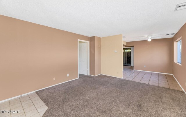 unfurnished room with a textured ceiling, ceiling fan, a wealth of natural light, and light colored carpet