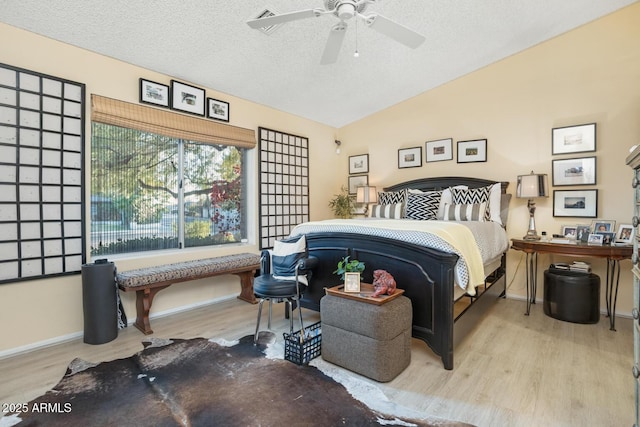 bedroom featuring a textured ceiling, vaulted ceiling, ceiling fan, and light hardwood / wood-style flooring