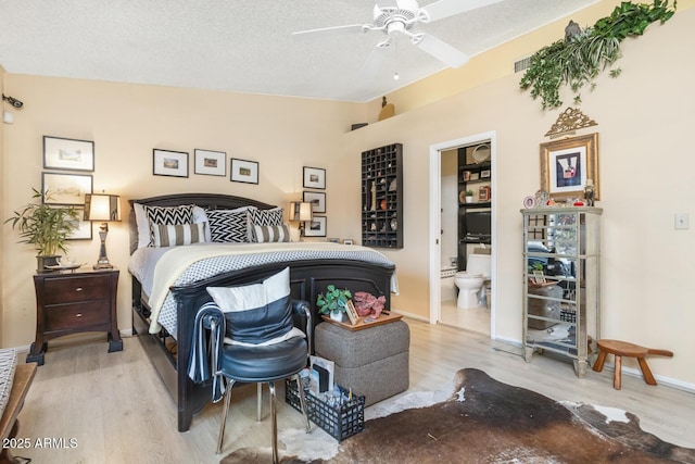 bedroom featuring light hardwood / wood-style floors, ensuite bath, a textured ceiling, and ceiling fan