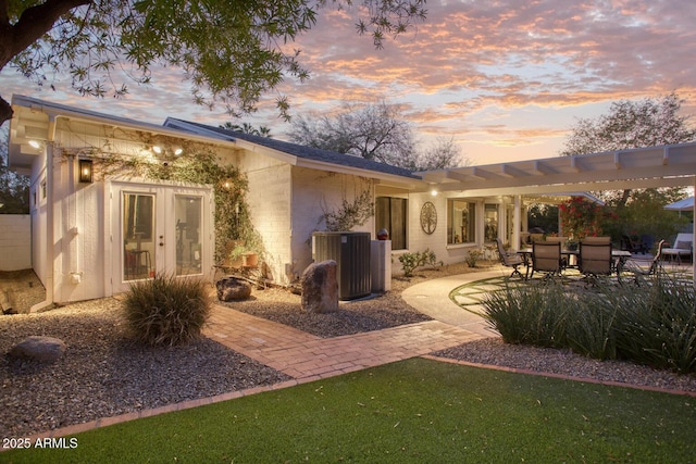 back house at dusk featuring a patio, french doors, and central air condition unit