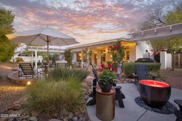 patio terrace at dusk featuring a pergola and a fire pit