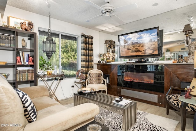 sitting room with light wood-type flooring, a textured ceiling, and ceiling fan with notable chandelier