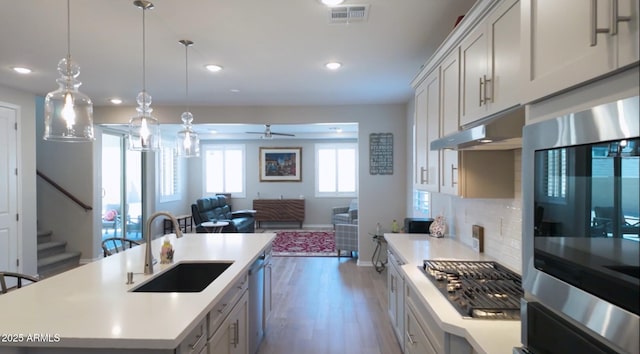 kitchen featuring a center island with sink, ceiling fan, appliances with stainless steel finishes, pendant lighting, and sink