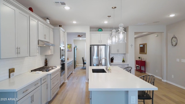 kitchen featuring a breakfast bar area, appliances with stainless steel finishes, tasteful backsplash, and a kitchen island with sink