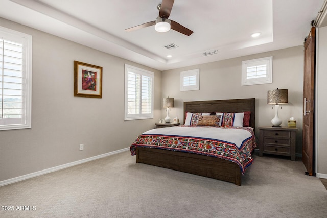 carpeted bedroom featuring ceiling fan, a tray ceiling, and multiple windows