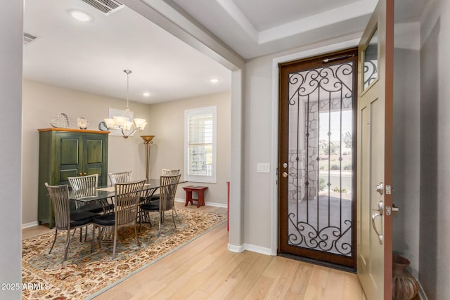 foyer entrance with light hardwood / wood-style floors and a chandelier