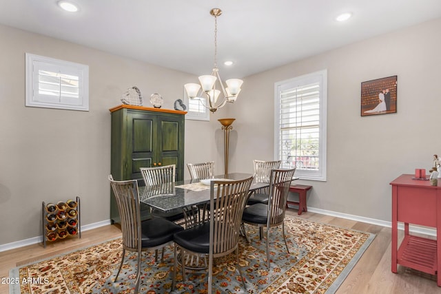 dining space featuring light wood-type flooring and an inviting chandelier