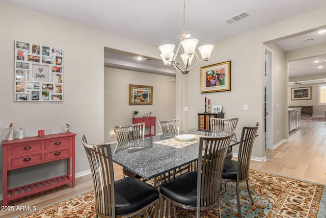 dining space featuring a notable chandelier and light wood-type flooring