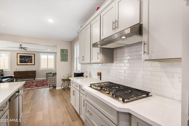 kitchen with ceiling fan, light wood-type flooring, decorative backsplash, and stainless steel appliances