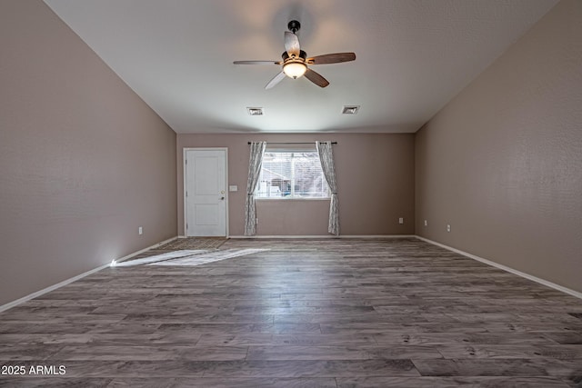 spare room with a ceiling fan, baseboards, visible vents, and dark wood-style flooring