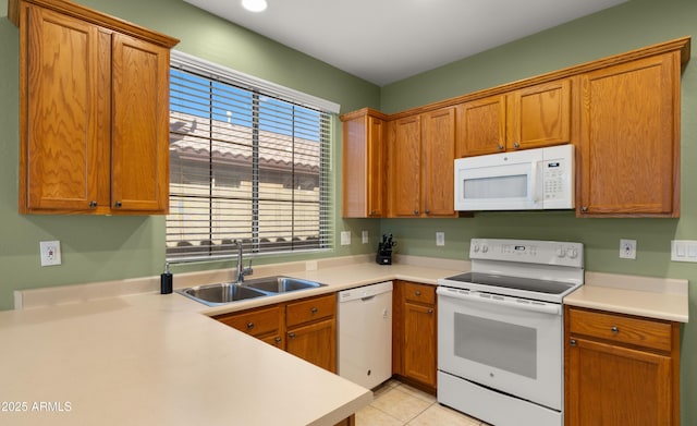 kitchen with brown cabinets, light countertops, light tile patterned flooring, a sink, and white appliances