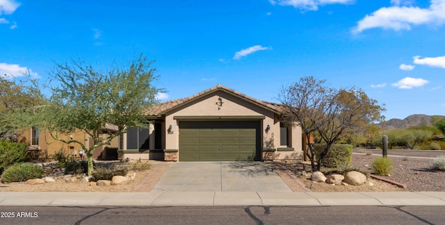 ranch-style home with a garage, driveway, a tile roof, a mountain view, and stucco siding