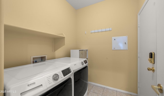 clothes washing area with laundry area, light tile patterned floors, baseboards, and washing machine and clothes dryer