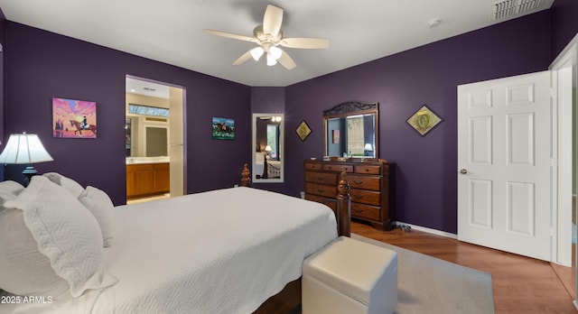 bedroom with ensuite bath, visible vents, a ceiling fan, and wood finished floors