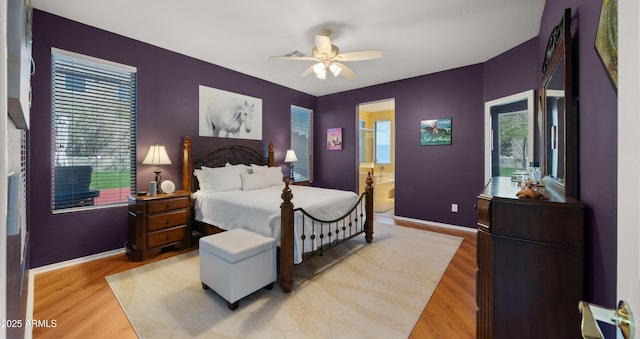 bedroom featuring multiple windows, light wood-style flooring, baseboards, and ensuite bathroom