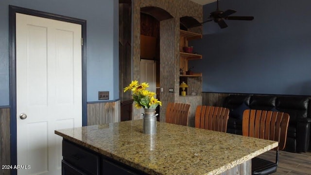 kitchen featuring ceiling fan, hardwood / wood-style floors, and light stone countertops