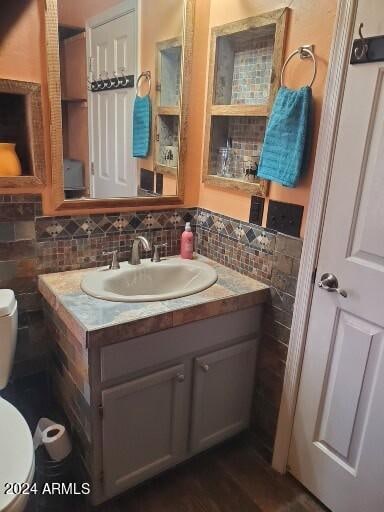 bathroom with hardwood / wood-style flooring, backsplash, toilet, and vanity