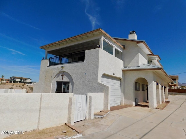 view of front of property with stucco siding, a standing seam roof, metal roof, a balcony, and driveway