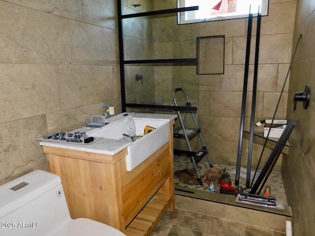 bathroom with toilet, vanity, and tile walls